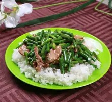 Stir-fried garlic shoots with pork over rice